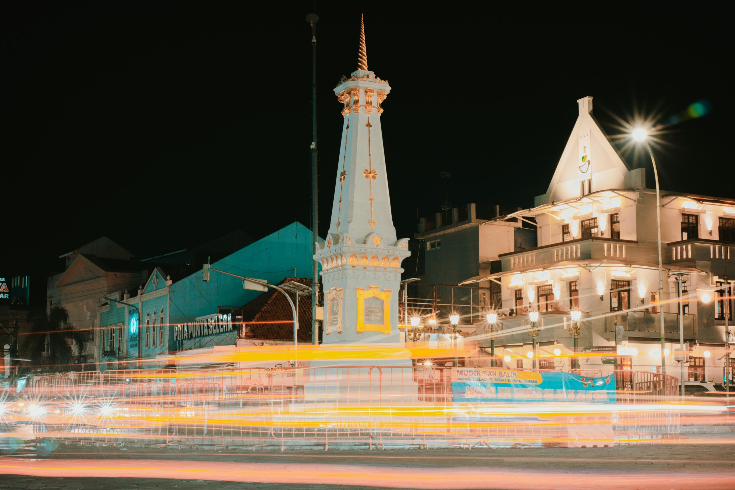 Captivating long exposure of Tugu Yogyakarta with vibrant traffic light trails at night showcasing urban life.