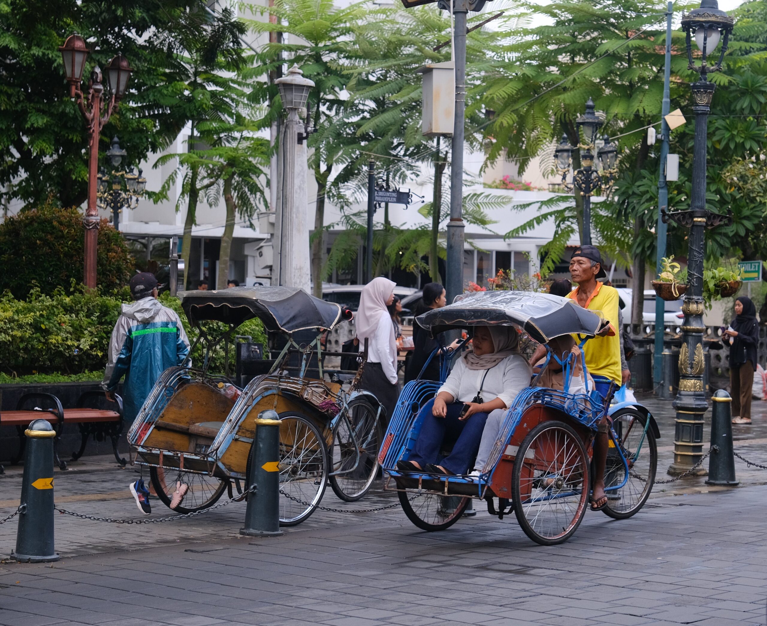 A vibrant street scene with traditional rickshaws and pedestrians in an urban setting.