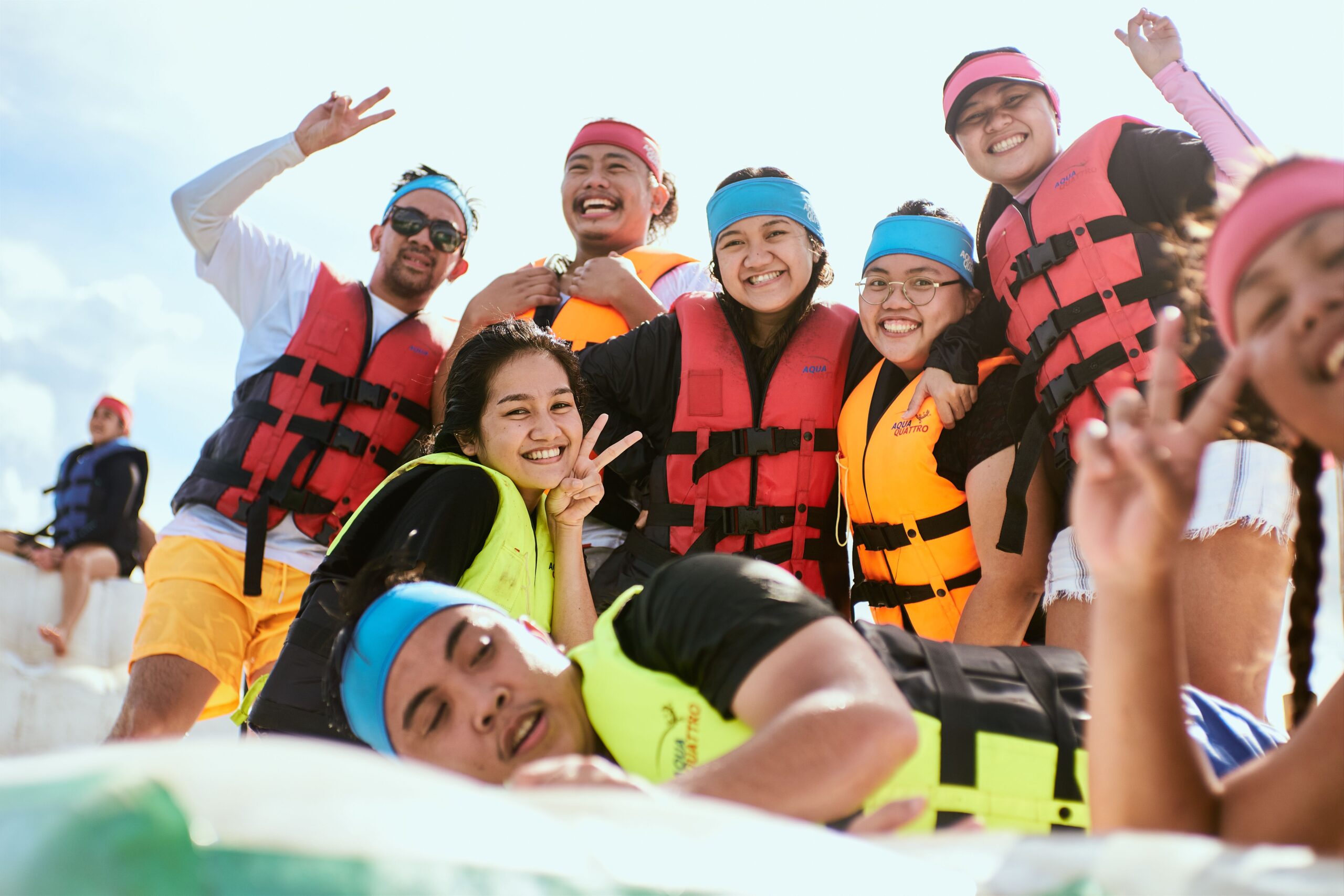 A lively group of friends wearing colorful life vests and headbands, enjoying an outdoor adventure.